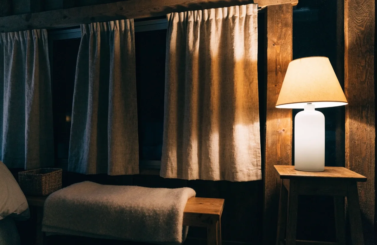 Warm lamplight on a quiet home office corner with guides stacked beside a valley window